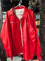 Full view of red jacket on hanger showing embroidery and patch