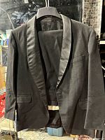 Black tuxedo jacket front view on hanger showing satin shawl lapel