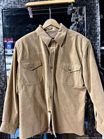 Full front view of tan suede jacket on hanger