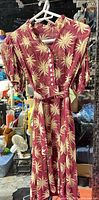 Full view of maroon palm-print dress on hanger