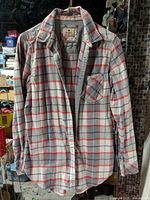 Full front view of plaid flannel shirt on hanger