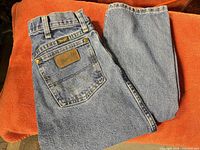 Full view of folded jeans showing back pocket, leather patch, overall color and fabric