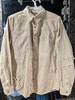 Full front view of Zara off-white distressed denim jacket on hanger