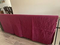 Full view of burgundy duvet cover draped over railing