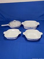Four Corning Ware cornflower dishes and glass lid displayed