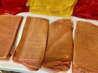 Four copper-gold mesh bundles with one bright gold bundle on white surface