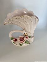 left front view showing swan form, raised roses, gold accents