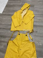 Jacket with hood laid open beside bib overalls