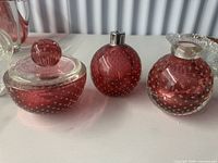 Three pink bullicante glass vanity pieces side by side