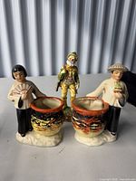 Front view of all three ceramic figurines showing design and attached pots