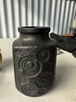 Full view of black ceramic vase with spiral relief