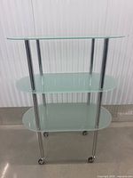 Front view of cart showing three frosted glass shelves and chrome frame