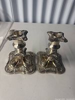Pair of ornate silver-tone candlesticks, full view