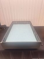 Top view of closed black showcase with glass lid showing blue velvet interior