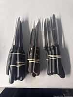 Three rubber-banded bundles of serrated steak knives on table