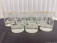 All six glasses grouped showing etching and gold rims
