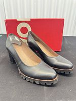Pair of black leather platform pumps in front of red Wonders box
