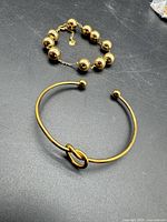 Overview of both gold-tone bracelets on black surface