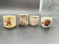 Front view of all four egg cups displaying designs and condition