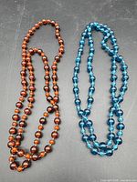 Full view of both necklaces laid flat showing colours and bead sizes
