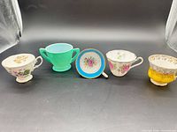 Group shot of all five items: four teacups and one saucer