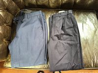Two pairs dress pants on leather couch, navy and charcoal