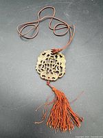 Full view of jade pendant on cord with tassel