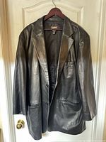 Front view of black leather blazer on hanger