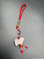 Full view of corded charm showing rose quartz pendant and bead tassel