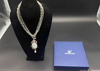 Necklace displayed on bust with box beside