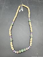 Full view of beaded necklace laid flat showing bead sequence and clasp