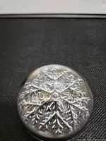 Top view of clear glass paperweight showing dendritic snowflake pattern