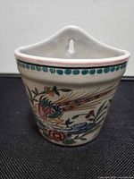 Front view of wall pocket showing bird and floral decoration