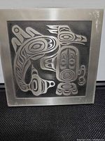 Front view of metal plaque showing sea monster design