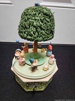 Front view showing base, tree, six child figures, winder key