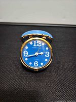 Clock front open showing blue dial, gold case