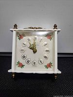 Front view showing dial, case, brass finials and feet