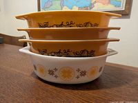 Stack of four Pyrex 043 casseroles showing three Old Orchard on top and one Town and Country on bottom