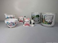 Group shot of creamer, sugar bowl, cat shakers and two Austrian mugs