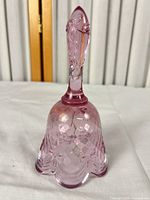 Full view of cranberry pink glass hand bell showing diamond optic body and scalloped rim