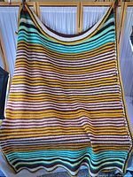 Full view of crocheted striped afghan hanging to show overall pattern and size