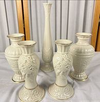 Front view of all five ivory Lenox bud vases showing designs and gold rims