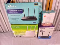 All four boxed items: TP-Link Archer A8 router, Kasa Smart Switch, TP-Link Archer C9 router, Netgear AC1000 router
