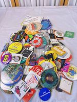 Pile of assorted promotional buttons showing variety of shapes, sizes and brands