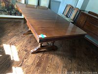 Antique solid wood dining table fully extended, showing overall tabletop and turned legs.