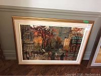 Full view of framed painting leaning against wall on hardwood floor