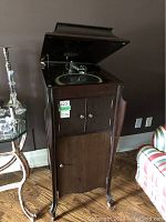 Front view of wooden cabinet with lid open showing turntable and tonearm