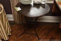 Metal round side table with plates and cups placed on top, showing overall shape and design.