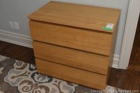 View of the dresser from the front showing three drawers and light wood finish with scuffs.