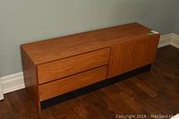 Front view of teak veneer dresser showing two drawers and two-door cabinet on black base